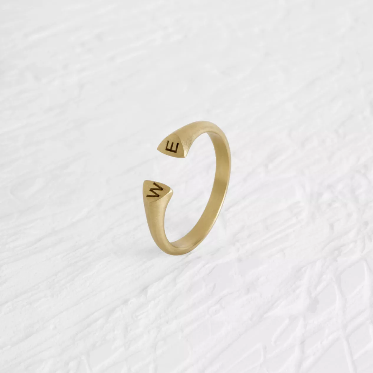 An incomplete gold band, engraved with the word "WE". This is a blend of a classy style with a fa...