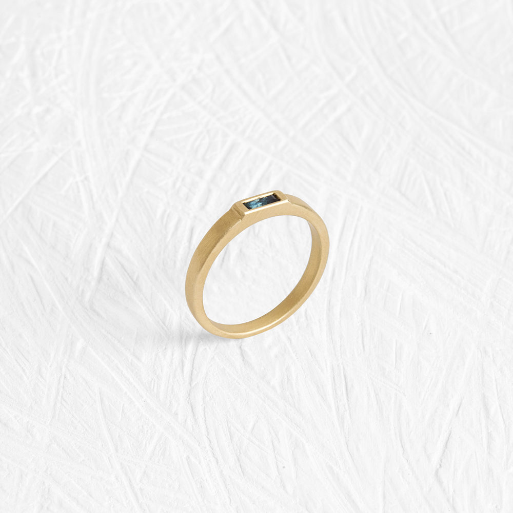 This sleek ring has a flattened bezel that is almost flush with the band and is set with a sapphire. - View 2