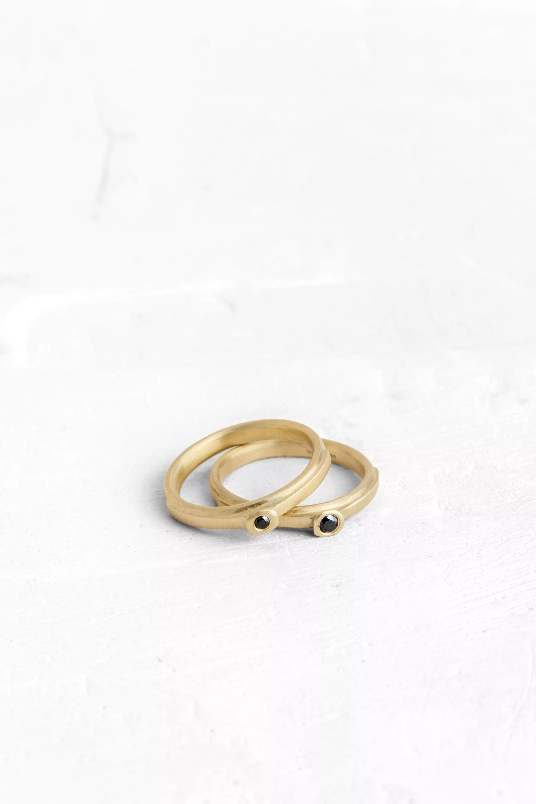A ring designed from layers of gold, a ring on a ring while the top layer is set with a black dia...