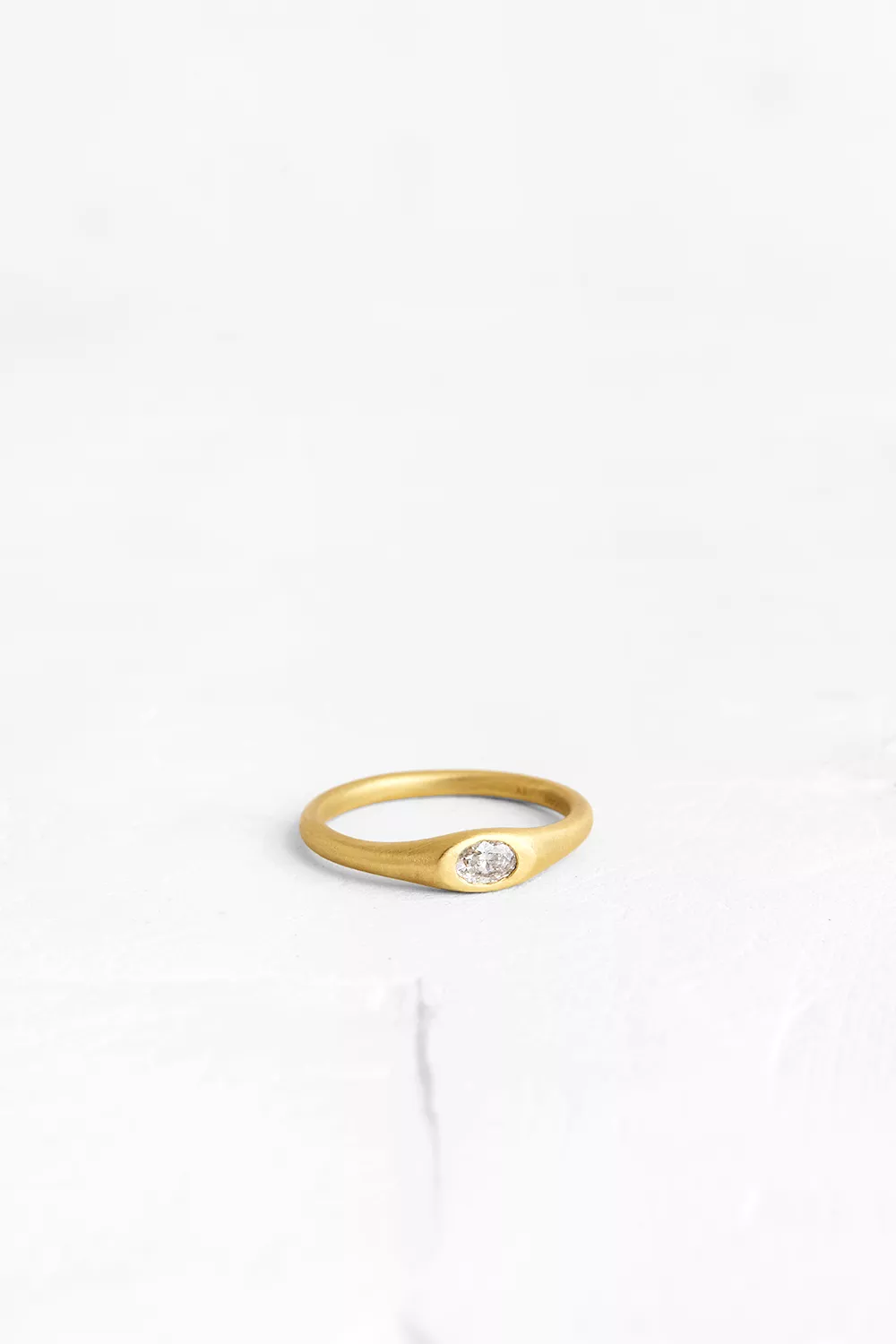 An 0.15 ct. white diamond set in an oval gold ring. A traditional design with a twist.