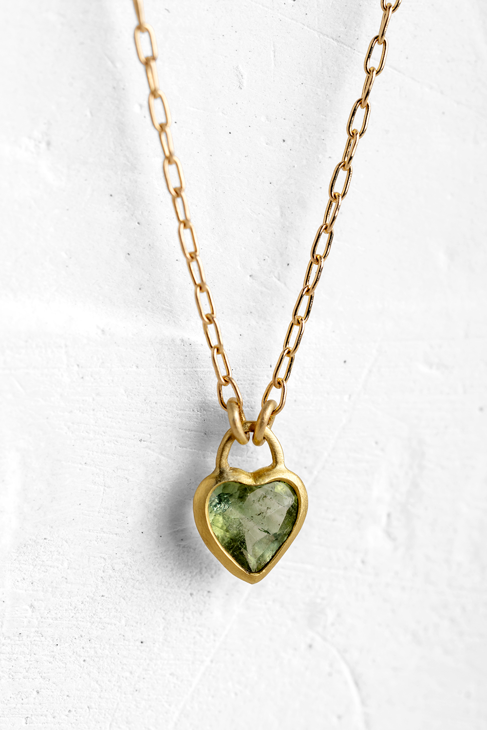 A handmade pendant is set with Green Tourmaline stone in a heart shape which hangs on a delicate ...