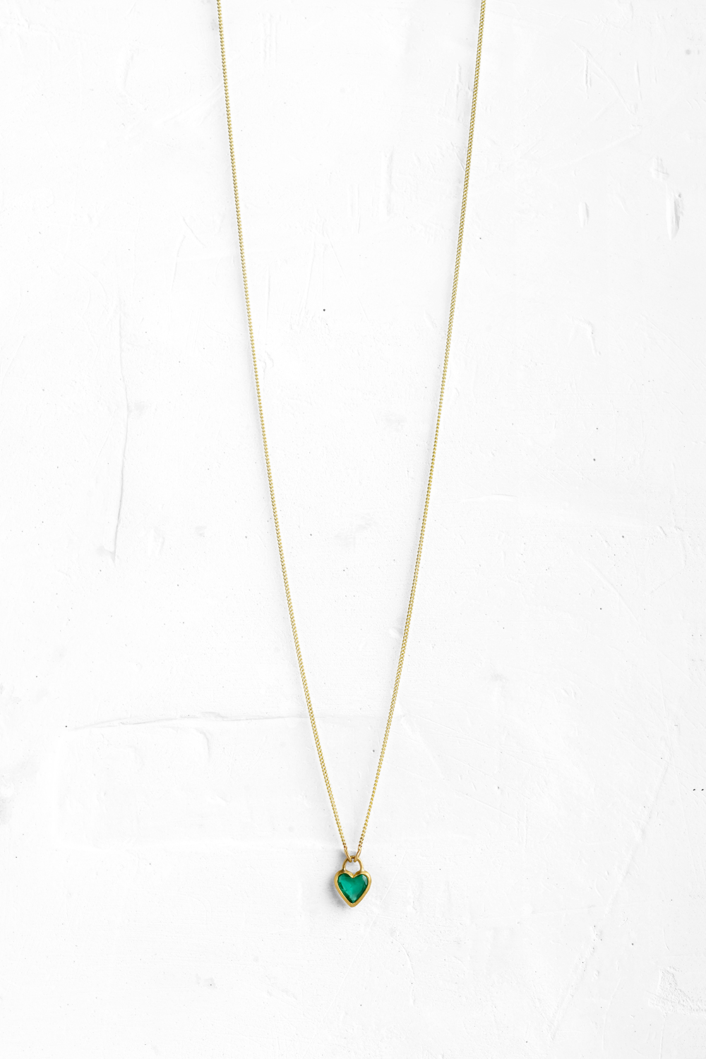 A handmade pendant is set with a Green Emerald in a heart shape which hangs on a delicate chain - View 2