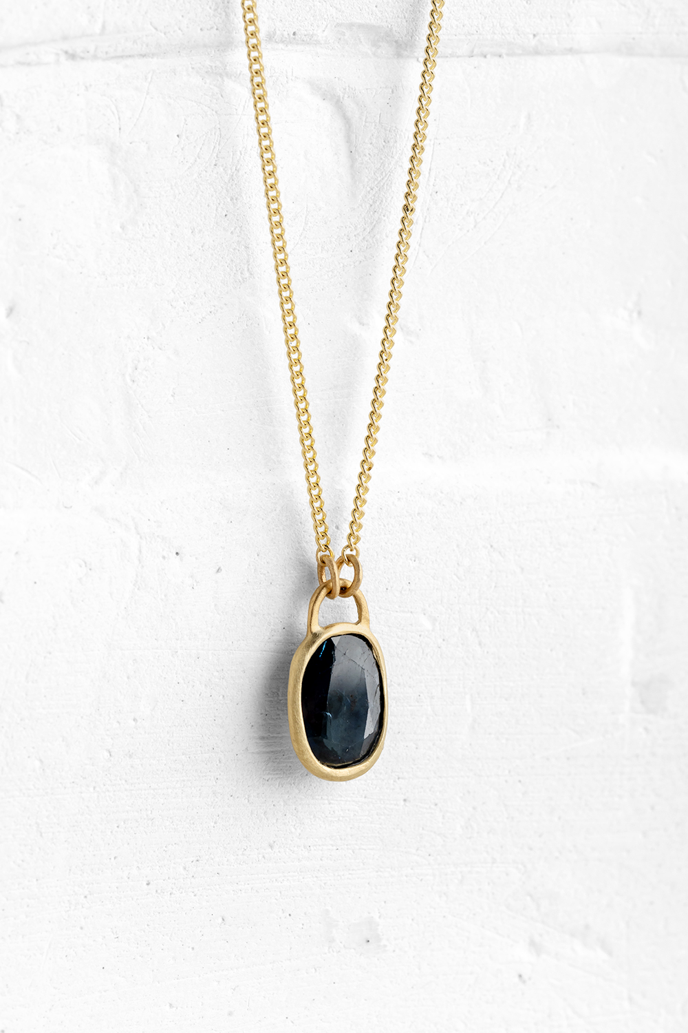 A handmade pendant is set with a deep Blue Saphire stone which hangs on a delicate chain