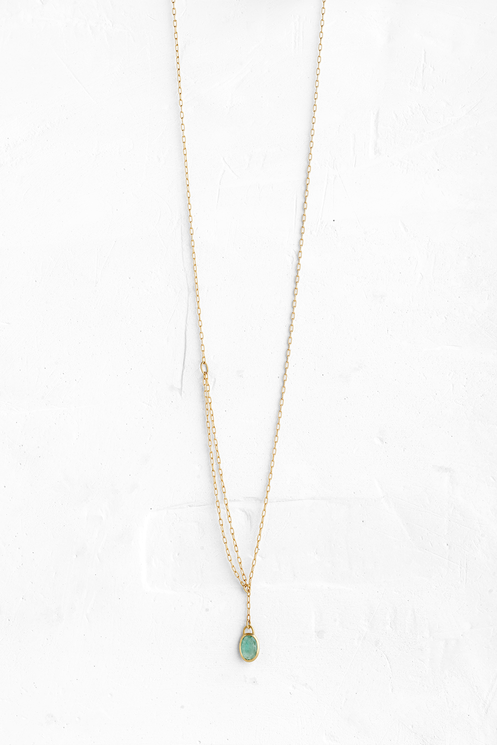 A handmade pendant is set with an oval one of a kind Emerald stone which hangs on a delicate chain - View 2