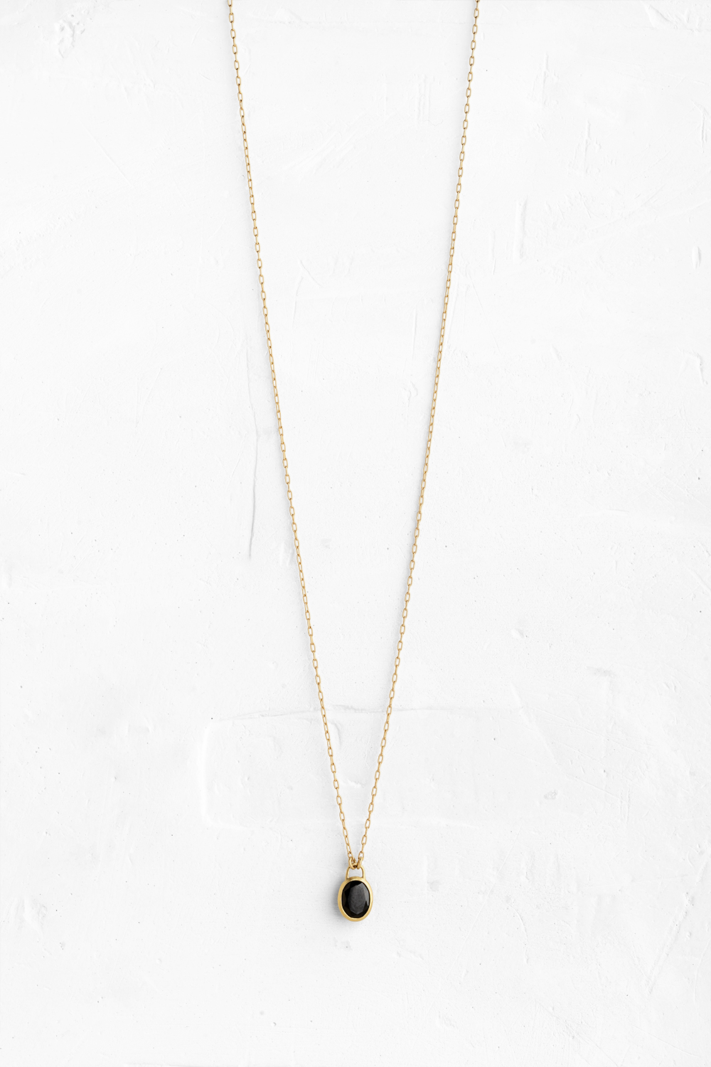 A handmade pendant set with a beautiful black Onix stone hanging on a delicate gold necklace - View 2