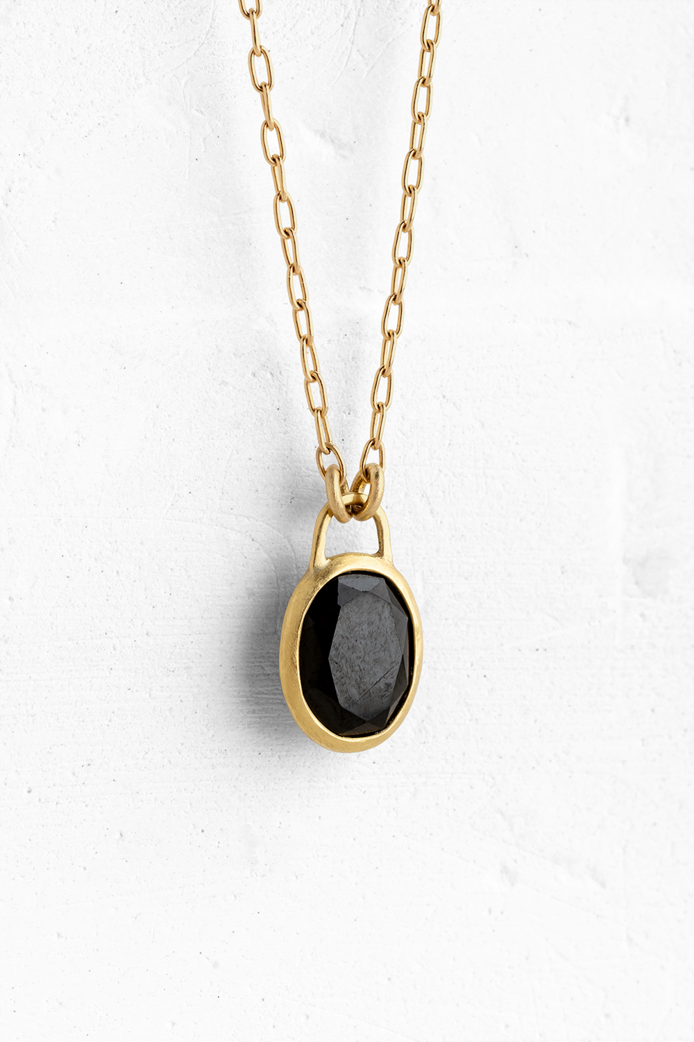 A handmade pendant set with a beautiful black Onix stone hanging on a delicate gold necklace