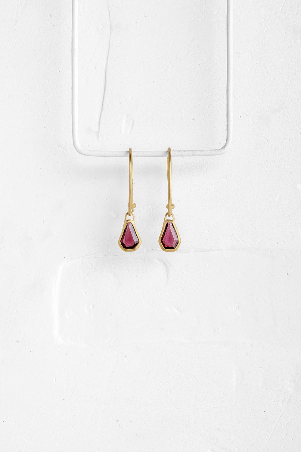 A pair of hexagonal pink Granet stones wrapped in gold hang from hand crafted wire hook

&nbsp;