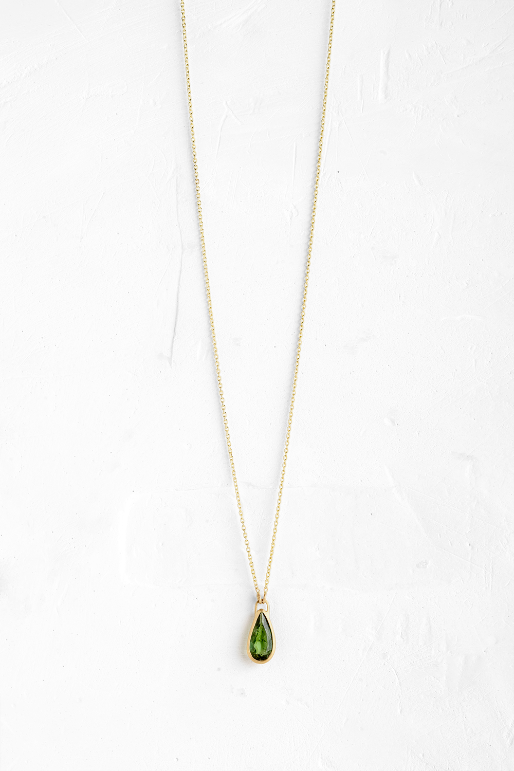 A handmade pendant is set with a Green Tourmaline stone which hangs on a delicate chain - View 2