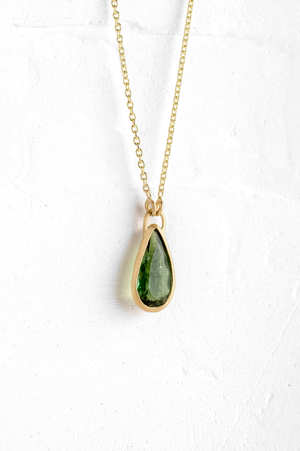 A handmade pendant is set with a Green Tourmaline stone which hangs on a delicate chain