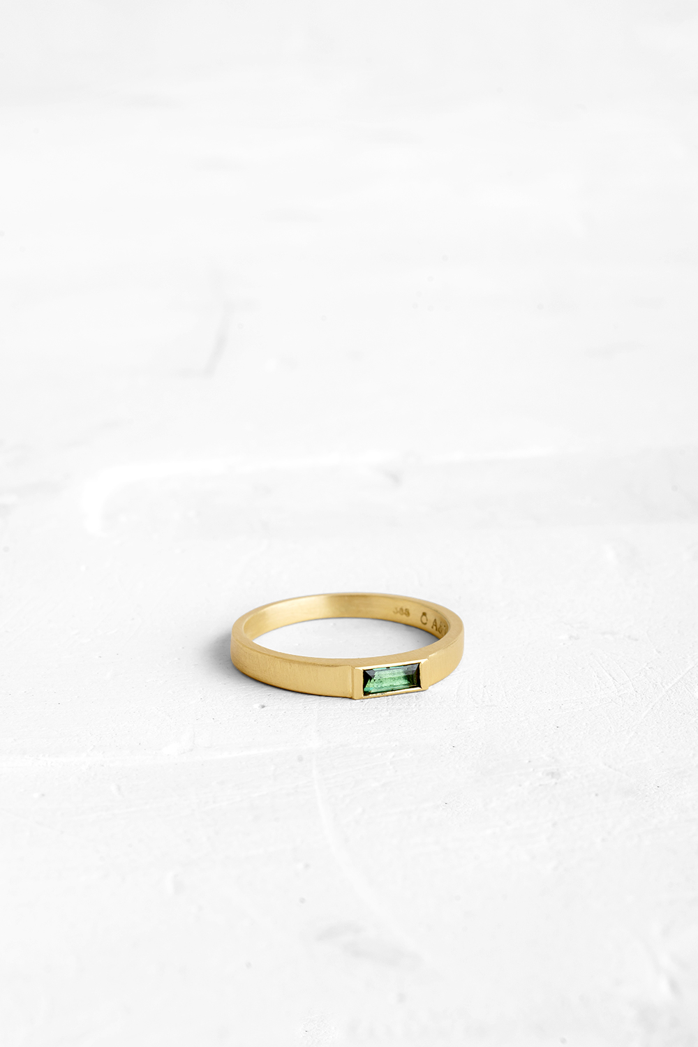 This sleek ring has a flattened bezel that is almost flush with the band and is set with a Green ...