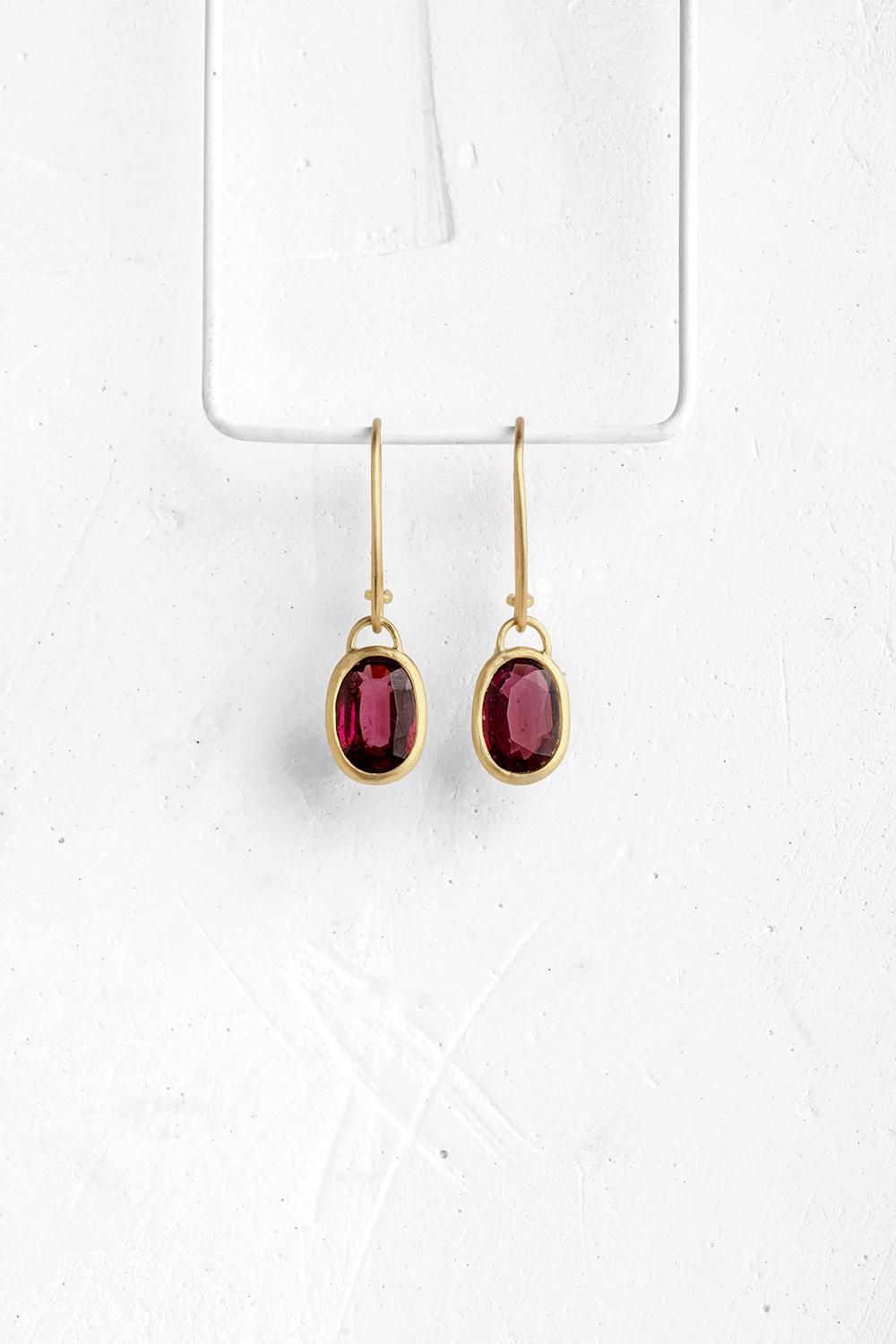 A pair of oval Rhodolite stones wrapped in gold hang from hand crafted wire hooks

&nbsp;