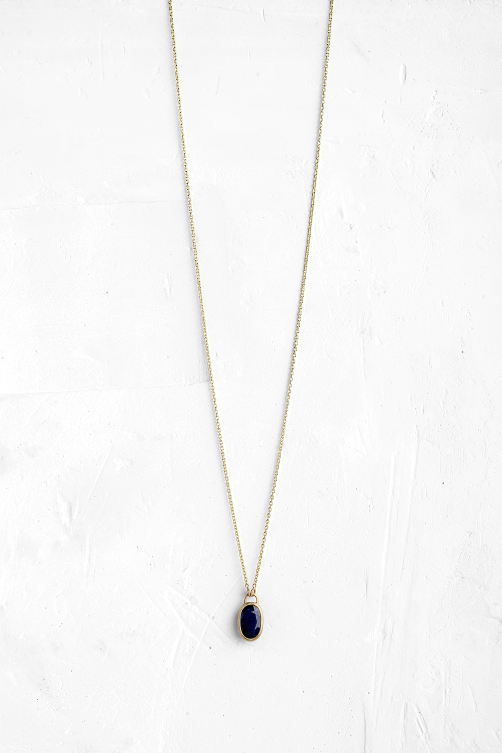 A handmade pendant is set with a Blue Saphire stone which hangs on a delicate chain. - View 2