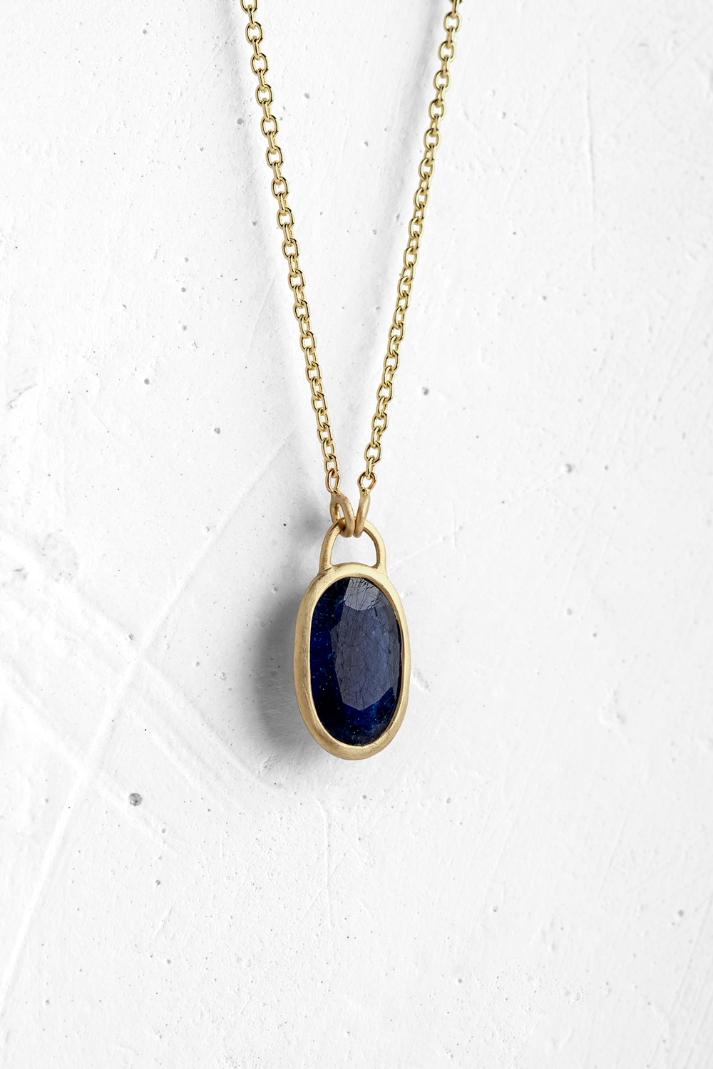 A handmade pendant is set with a Blue Saphire stone which hangs on a delicate chain.