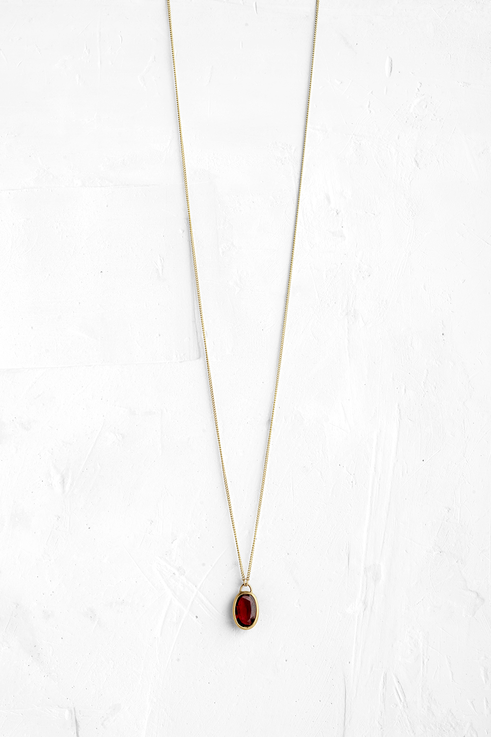 A handmade pendant is set with a deep pink Rhodolite stone which hangs on a delicate chain - View 2