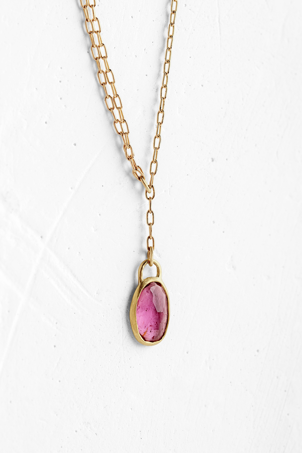 A handmade pendant is set with an oval shape Pink Tourmaline stone which hangs on a delicate chain