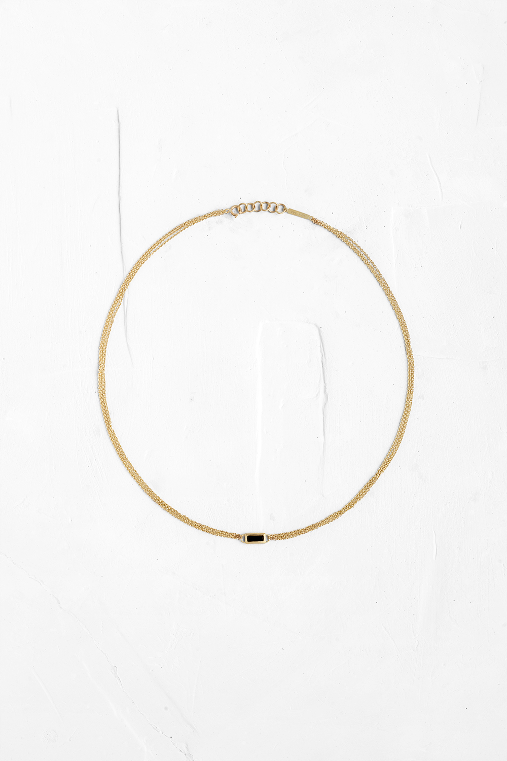 Luxurious, vintage look necklace made up of three small-link chains inlaid with a rectangular gem...